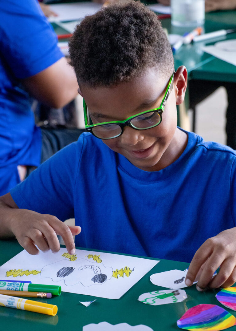 Kid doing arts and crafts with colorful markers